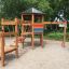 Ensemble de jeu en bois Six Angle with Suspension Bridge single slide dans une aire de jeux sablonneuse.